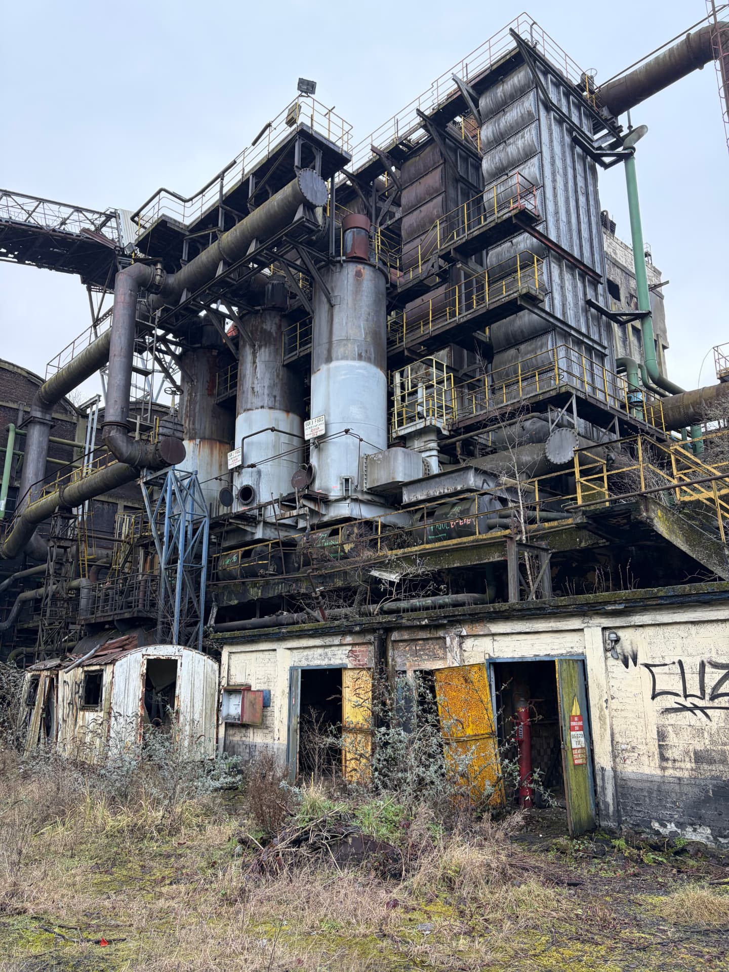 Ancienne installation industrielle désaffectée avec structures métalliques et tuyauteries corrodées